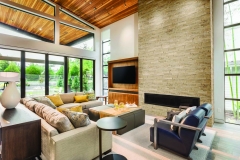 Beautiful living room interior with vaulted ceilings, hardwood floors, sliding glass doors,  and fireplace in new, modern luxury home
